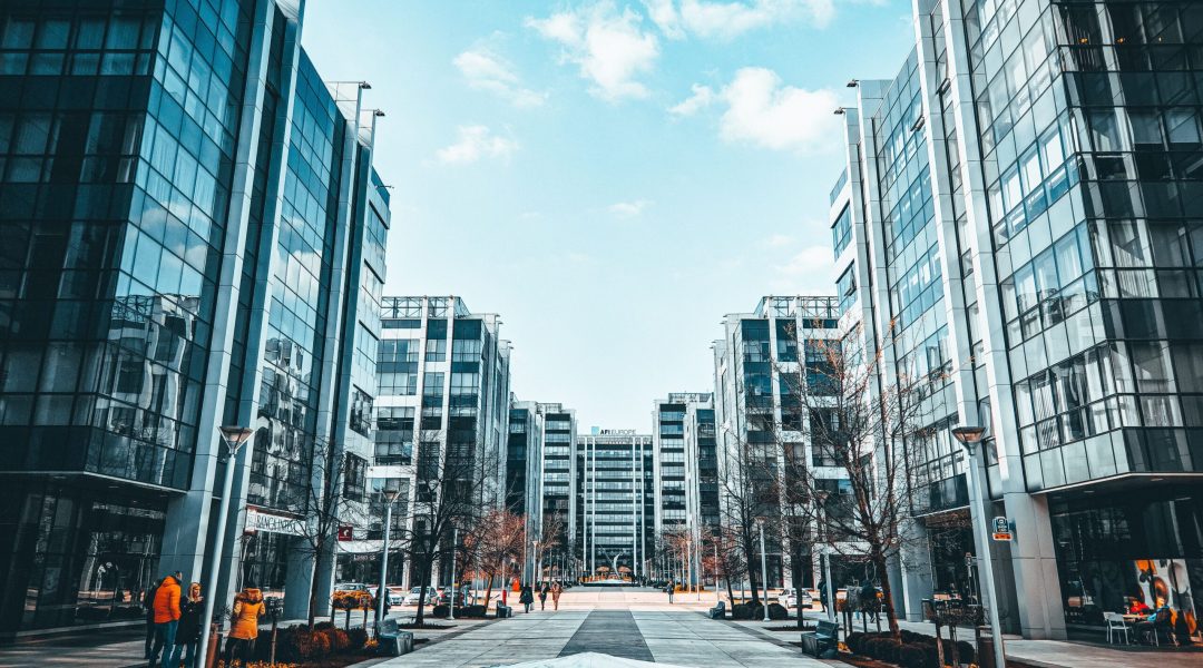 Contemporary urban environment featuring modern glass office buildings along a sidewalk.