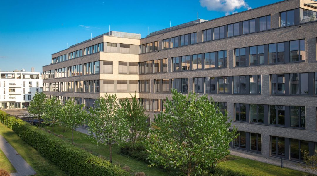 Exterior view of contemporary office buildings in Cologne, Germany, under a clear blue sky.