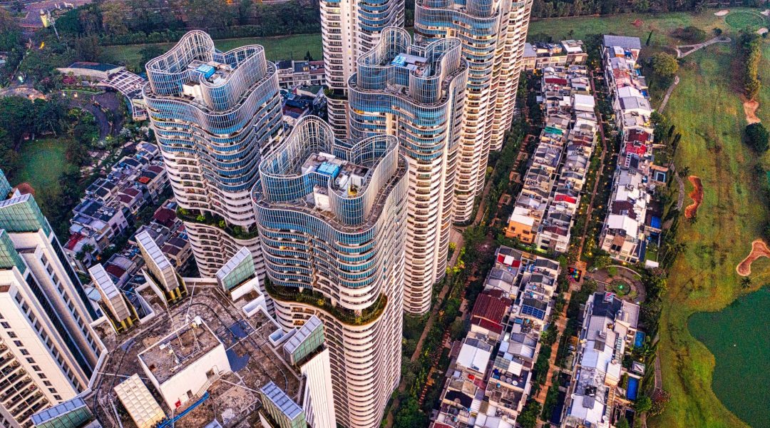 High-angle drone shot of Jakarta's modern skyscrapers and adjacent residential area.
